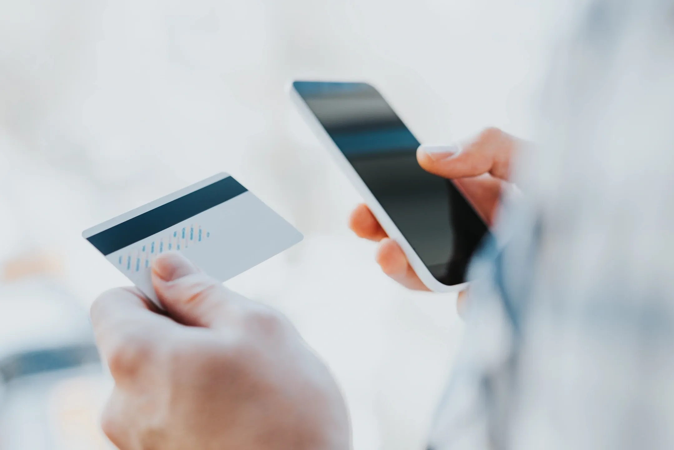 Person using smartphone and credit card for online payment.