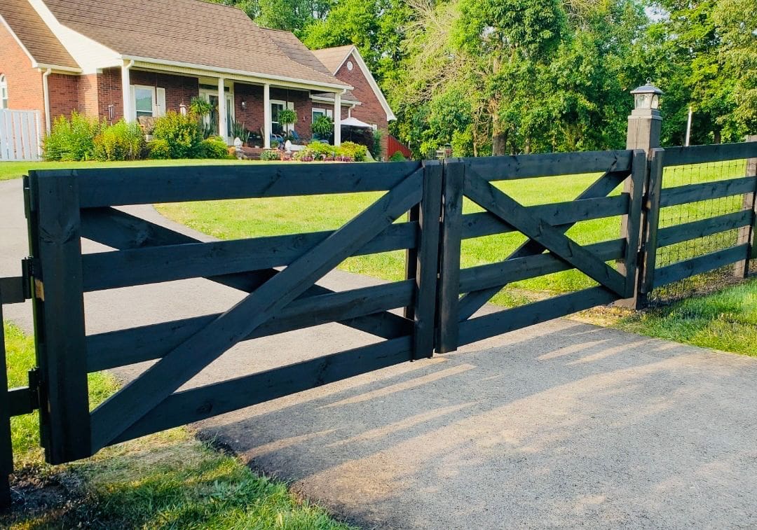 Black wooden gate with diagonal crossbars at a house entrance.