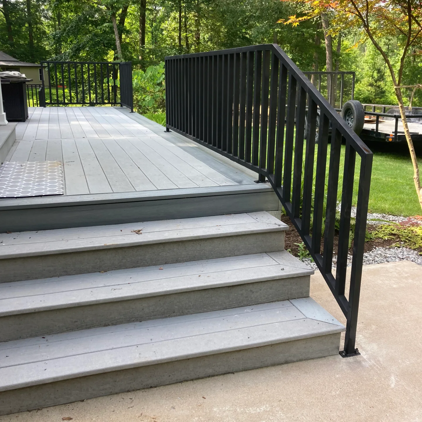 Outdoor stairs with black metal railing leading to a porch.