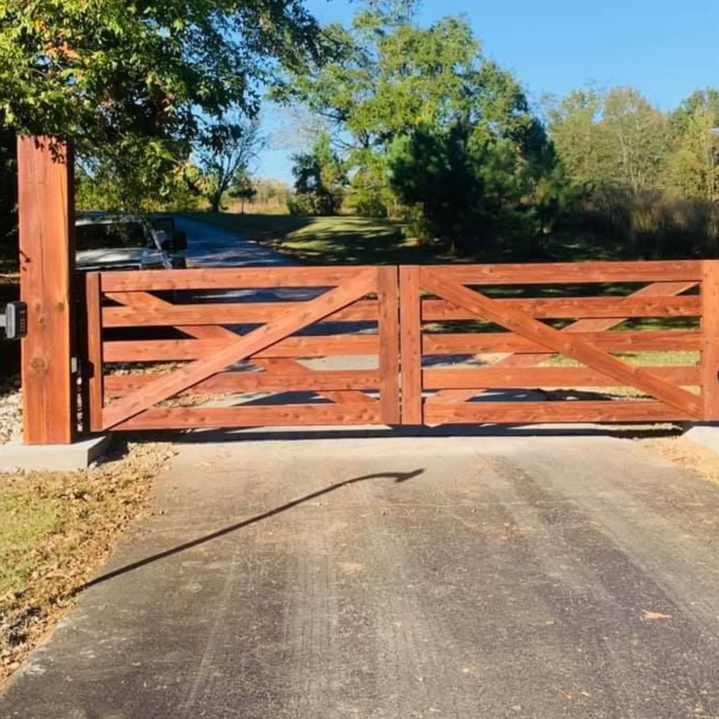 Wooden gate with a diagonal cross design at driveway entrance.